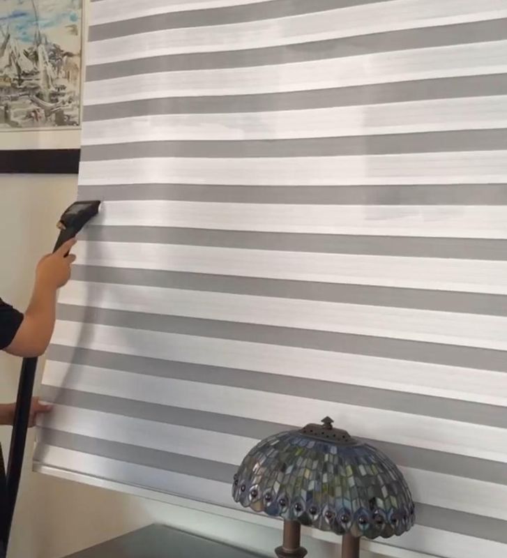 Técnico limpiando una cortina zebra con vapor